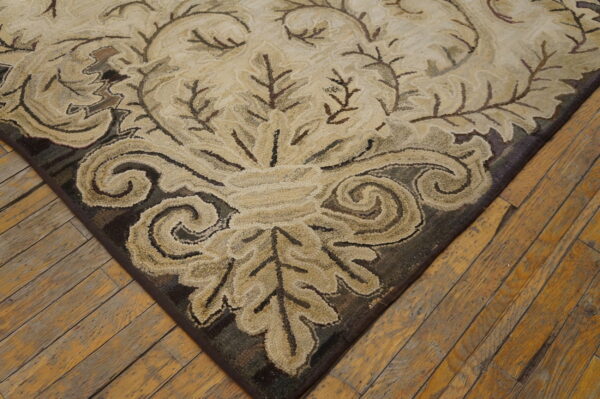 Beige and dark brown traditional foliate rug with textured looped pile on worn wood flooring.