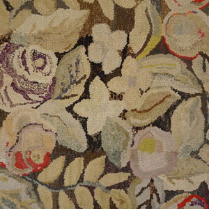 Textured hooked rug detail featuring large, dense floral and leaf motifs in beige, brown, and purple.