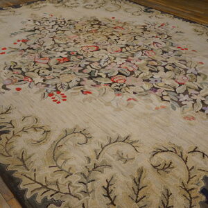 A large beige rug featuring a dense floral central design and scrolled borders rests on wood flooring.