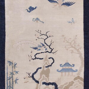 Cream rug with a navy border, featuring a blue and taupe pattern of a bird, trees, and pagoda.