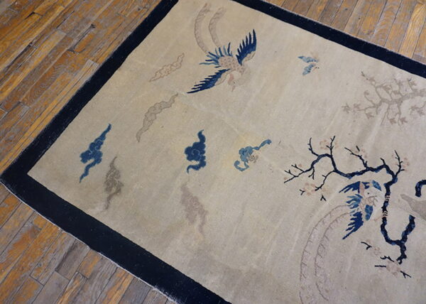 Low-pile beige rug featuring blue birds, taupe clouds, and a dark border, set against wood planks.