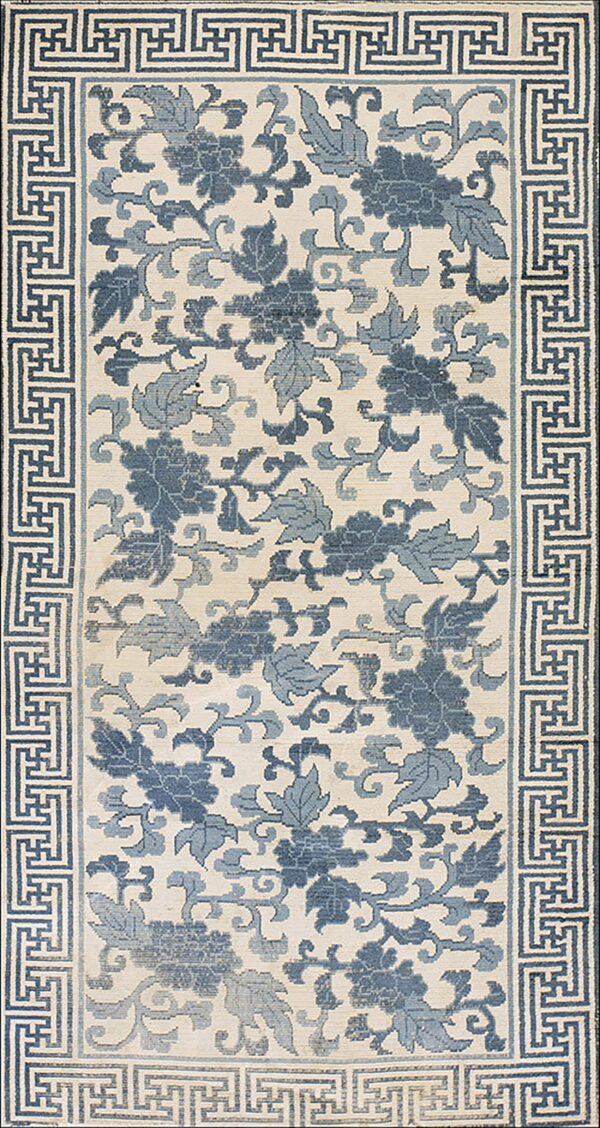 Cream rug with deep and light blue floral designs surrounded by a geometric key border.