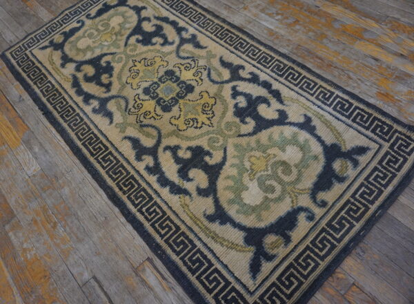 Navy, tan, and green runner rug featuring a detailed scroll pattern and greek key border on distressed wood planks.