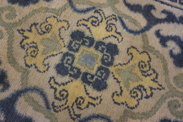 Low-pile rug detail showing beige, dark blue, and yellow stylized floral and scrolling patterns.