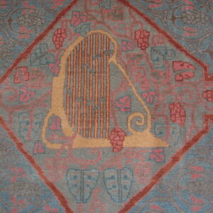 A muted gray-blue rug features a central diamond medallion with a stylized gold harp and pink floral patterns.