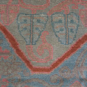 Geometric rug texture detail in muted green, dusty blue, terracotta, and subtle pink accents.