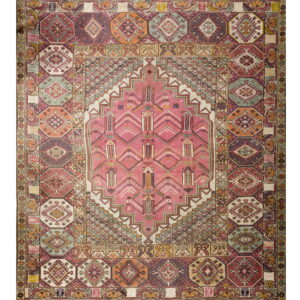 A multicolored geometric rug featuring a large pink central medallion and borders of repeating octagonal motifs.