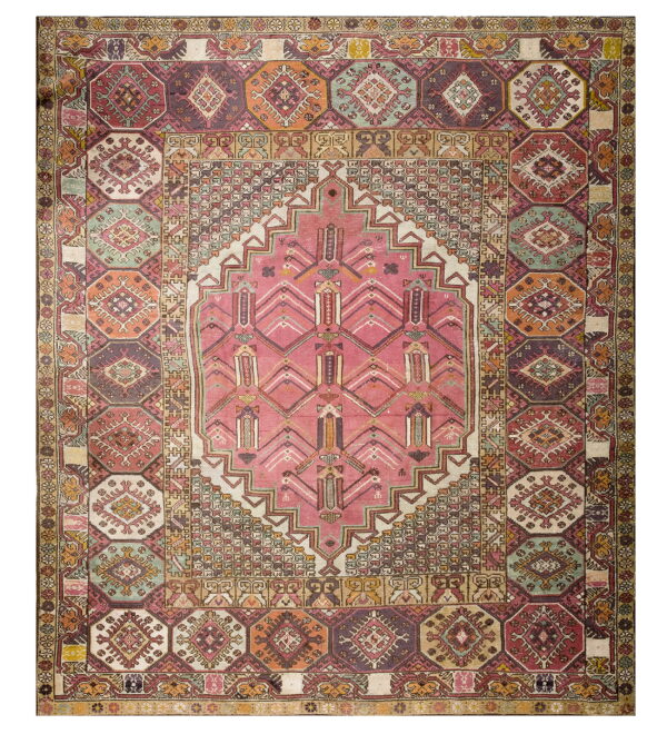 A multicolored geometric rug featuring a large pink central medallion and borders of repeating octagonal motifs.