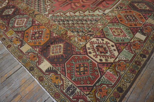 Geometric rug with octagonal medallions in rust, green, and orange, on distressed gray wood flooring.