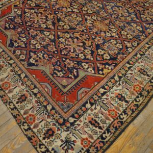 Close-up of a detailed red, blue, and cream patterned rug corner on distressed wooden floorboards.