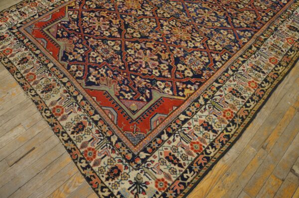 Close-up of a detailed red, blue, and cream patterned rug corner on distressed wooden floorboards.