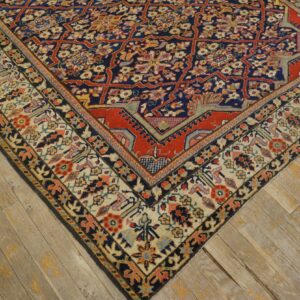 Ornate navy and red floral geometric rug shown on wide weathered wood planks.