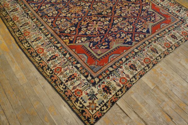 Ornate navy and red floral geometric rug shown on wide weathered wood planks.