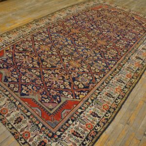Navy and red floral lattice rug with a beige border displayed on distressed yellow wooden planks.
