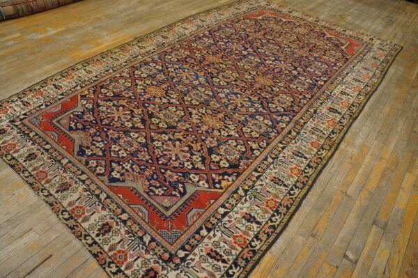 Navy and red floral lattice rug with a beige border displayed on distressed yellow wooden planks.