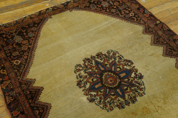 A gold central medallion rug with complex dark borders rests on rustic wooden planks.