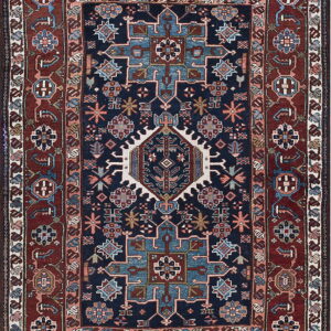 Navy blue rug with geometric medallions and stylized flowers on a dark red and light blue ground.