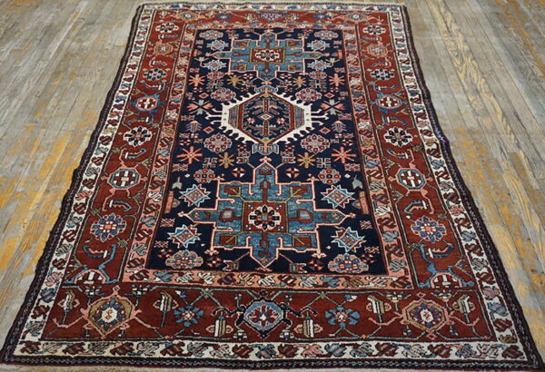 Navy blue and rust red geometric patterned rug displayed on light-colored wood planks.