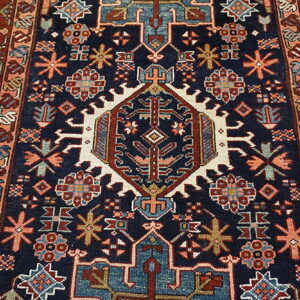 Dark navy rug with a detailed geometric pattern in red, teal, cream, and salmon colors.