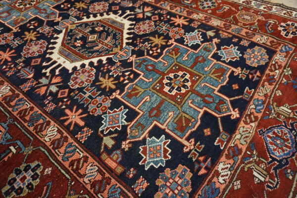 Detailed view of a rug showing a navy blue field with teal, rust, and cream geometric tribal patterns.