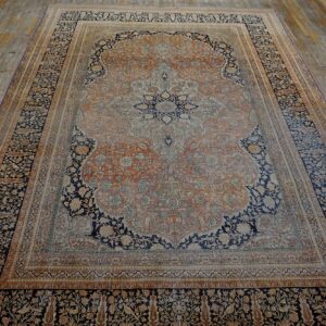 Traditional rug in navy blue, terracotta, and cream featuring a complex central medallion on wood planks.