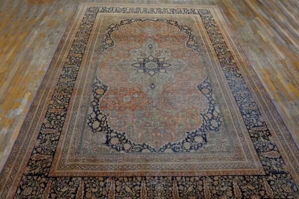 Traditional rug in navy blue, terracotta, and cream featuring a complex central medallion on wood planks.