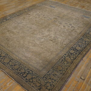 A large, distressed beige and navy patterned rug lies on rustic wooden floorboards.