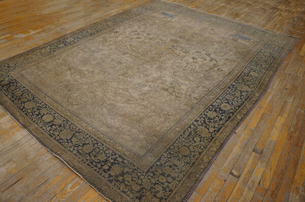 A large, distressed beige and navy patterned rug lies on rustic wooden floorboards.