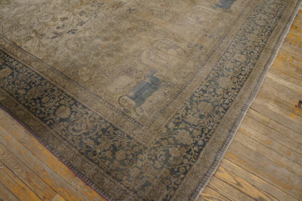 Distressed beige rug featuring faded blue animal motifs and a dark floral border on wooden floors.