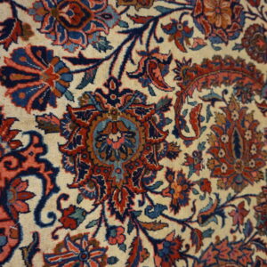 Detailed view of a complex floral and vine pattern in red, navy blue, and teal on a cream background.