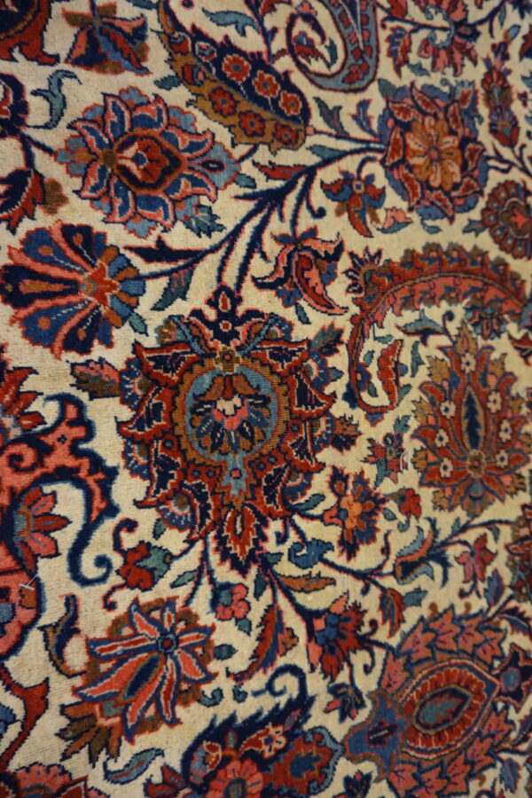 Detailed view of a complex floral and vine pattern in red, navy blue, and teal on a cream background.