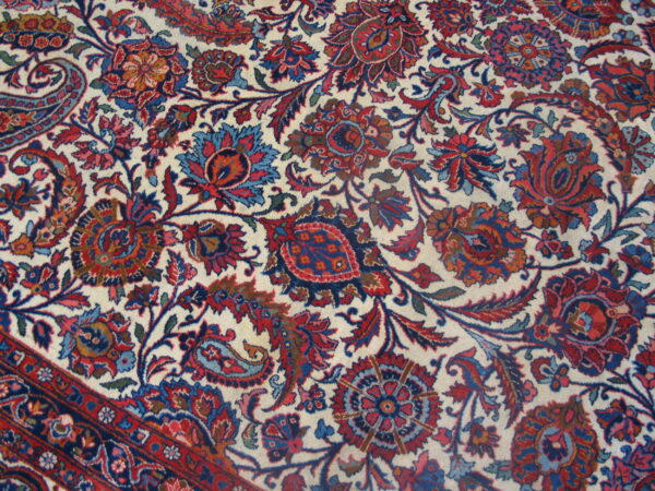 Intricate red and blue floral pattern on a cream field, showing a corner section and the multi-banded border.