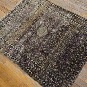 Ornate medallion rug in purple and faded gold colors resting on rustic wood plank flooring.