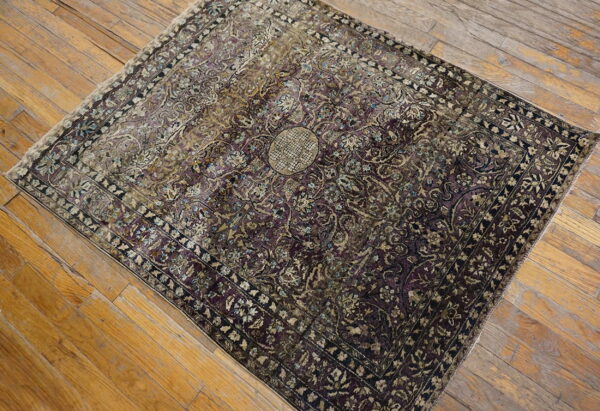 Ornate medallion rug in purple and faded gold colors resting on rustic wood plank flooring.