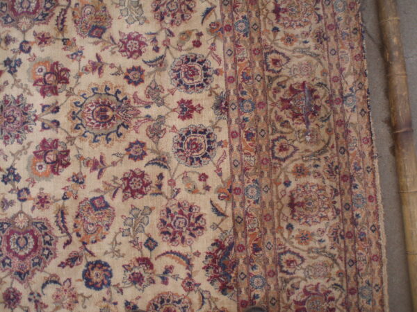 Traditional beige rug featuring low pile floral and medallion patterns accented in maroon, blue, and gold.