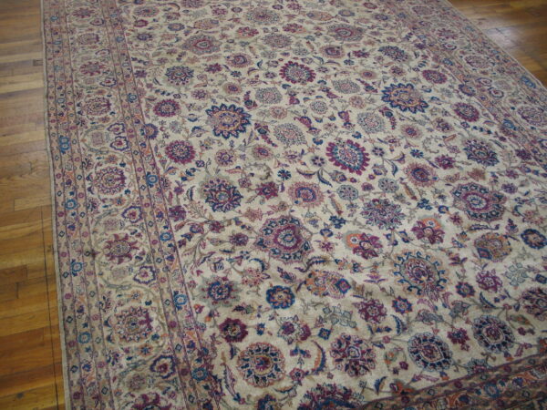 Large low-pile rug with a detailed floral pattern in ivory, maroon, and dark blue on wood planks.