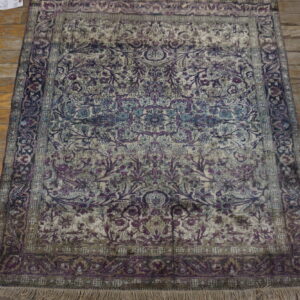 Ornate rug with purple, teal, and beige floral patterns rests on wide distressed wood planks.