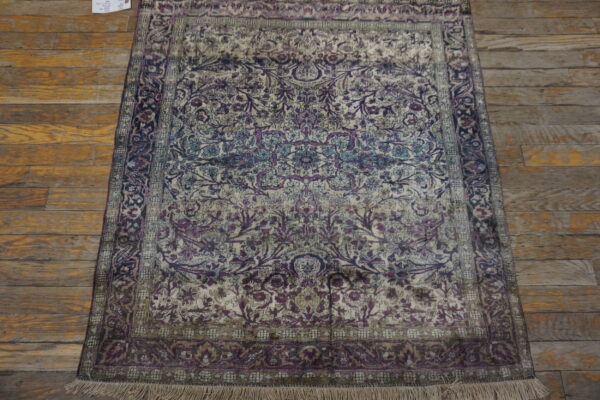 Ornate rug with purple, teal, and beige floral patterns rests on wide distressed wood planks.