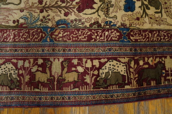 Detail of a red and cream rug border featuring running animals and blue geometric patterns over wood planks.
