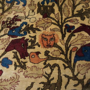 Cream rug patterned with dense brown vines, blue and maroon animals, and stylized human faces.