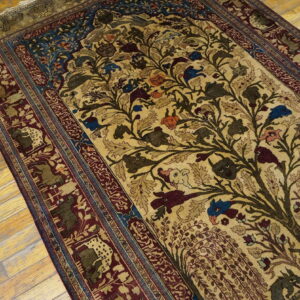 Beige rug featuring a detailed Tree of Life and animal pattern in burgundy, blue, and brown on wood floors.
