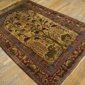 Gold Tree of Life rug with animal motifs and a deep red border rests on distressed light wood flooring.