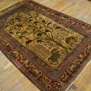 Gold and burgundy rug with a detailed tree of life and animal pattern rests on worn wood planks.