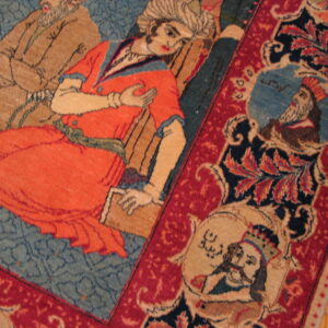 Low-pile rug detail showing figures in orange and tan on a blue field surrounded by a red border.