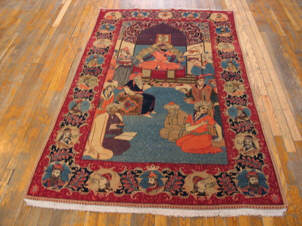 Red and blue figural rug with a central court scene and portrait border on light hardwood floors.