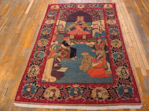 Red and blue pictorial rug with a central court scene and portrait borders on hardwood floors.