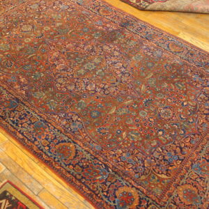 A large red and blue ornate rug with a dense floral design on hardwood flooring.