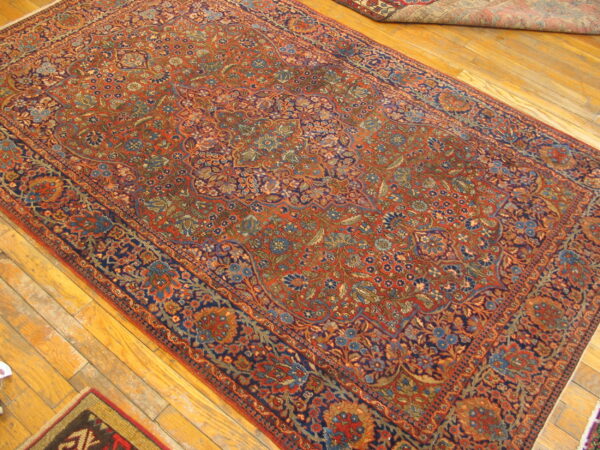 A large red and blue ornate rug with a dense floral design on hardwood flooring.