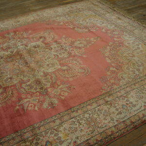 Faded rose traditional rug with ornate ivory floral patterns displayed on distressed wood planks.