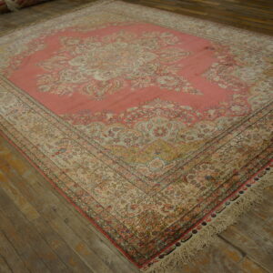 Ornate pink and cream traditional medallion rug rests on distressed dark wood plank flooring.
